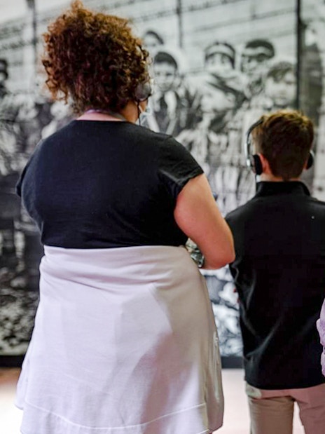 Visitors with headphones viewing Auschwitz Birkenau Memorial Museum exhibit.