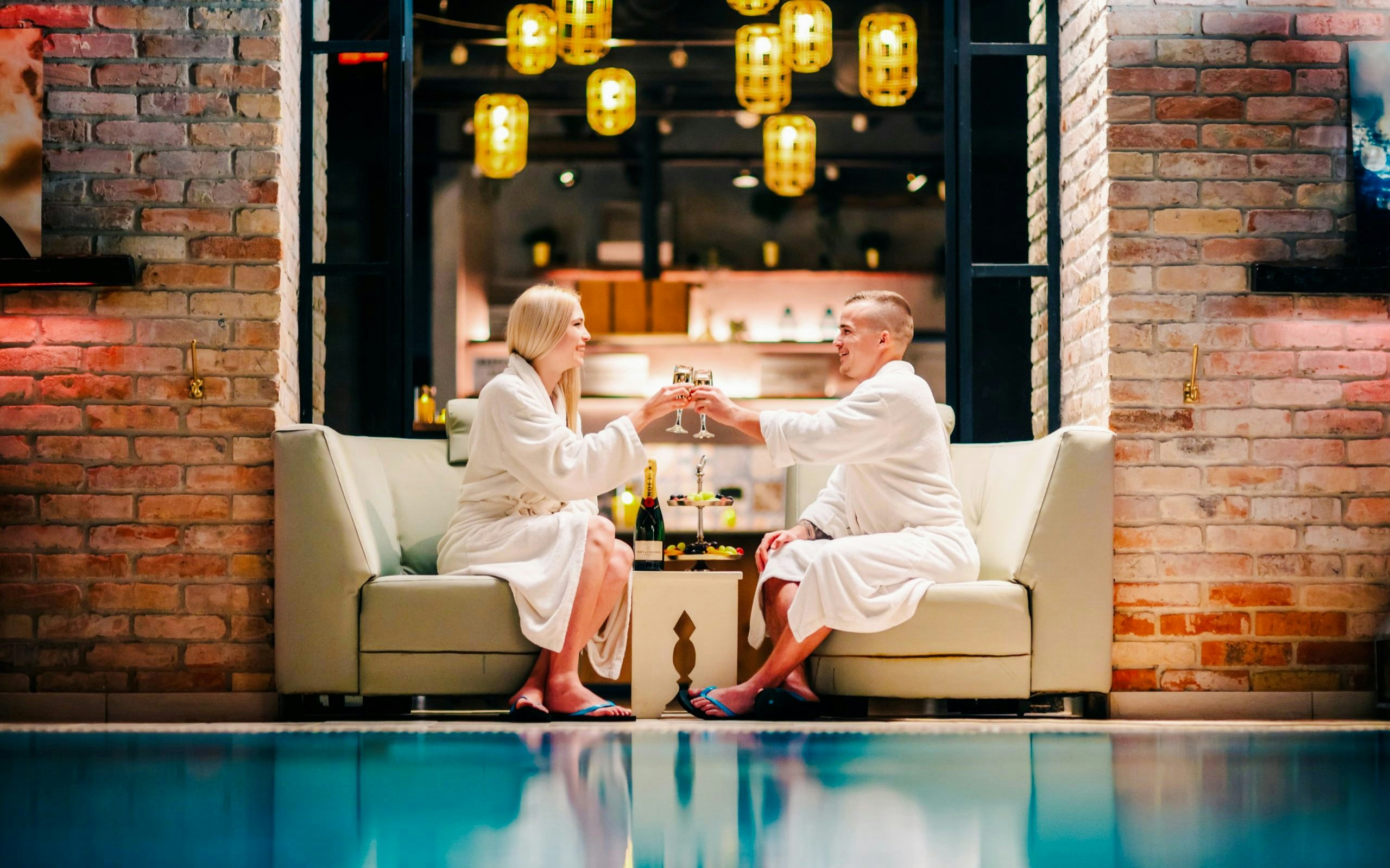 Guests toasting with champagne at Mandala Day Spa near a pool.