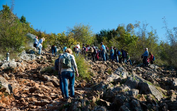 Hikers ascending rocky path on Apparition Hill, Bosnia and Herzegovina.