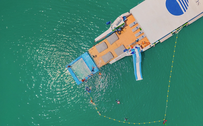 Aerial view of a party cruise deck with a slide and swimming area in Phang Nga Bay.