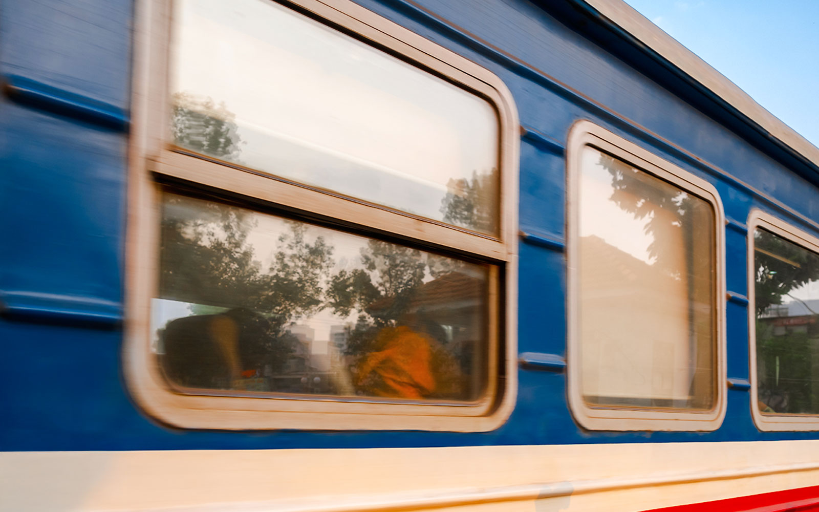 Gia Lam train carriage with blurred trees reflecting in windows.