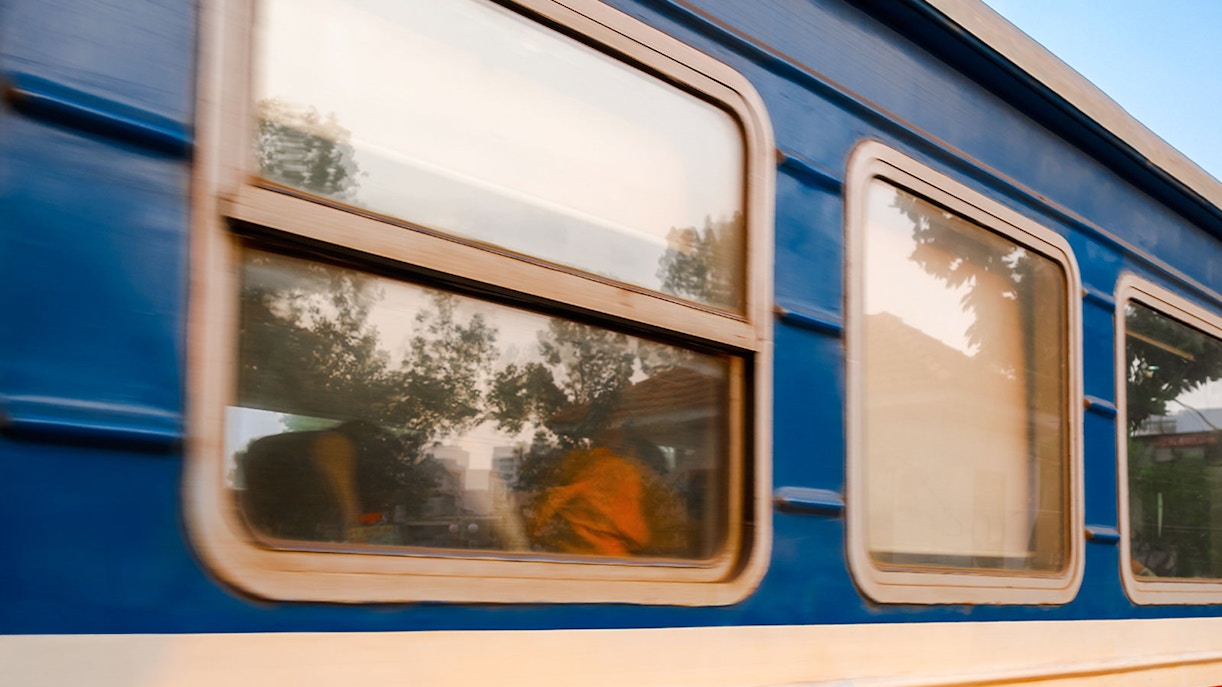 Gia Lam train carriage with blurred trees reflecting in windows.