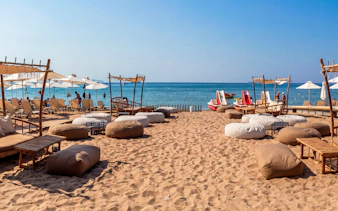 Beachfront seating with umbrellas and loungers on Sounion Half-Day Tour.