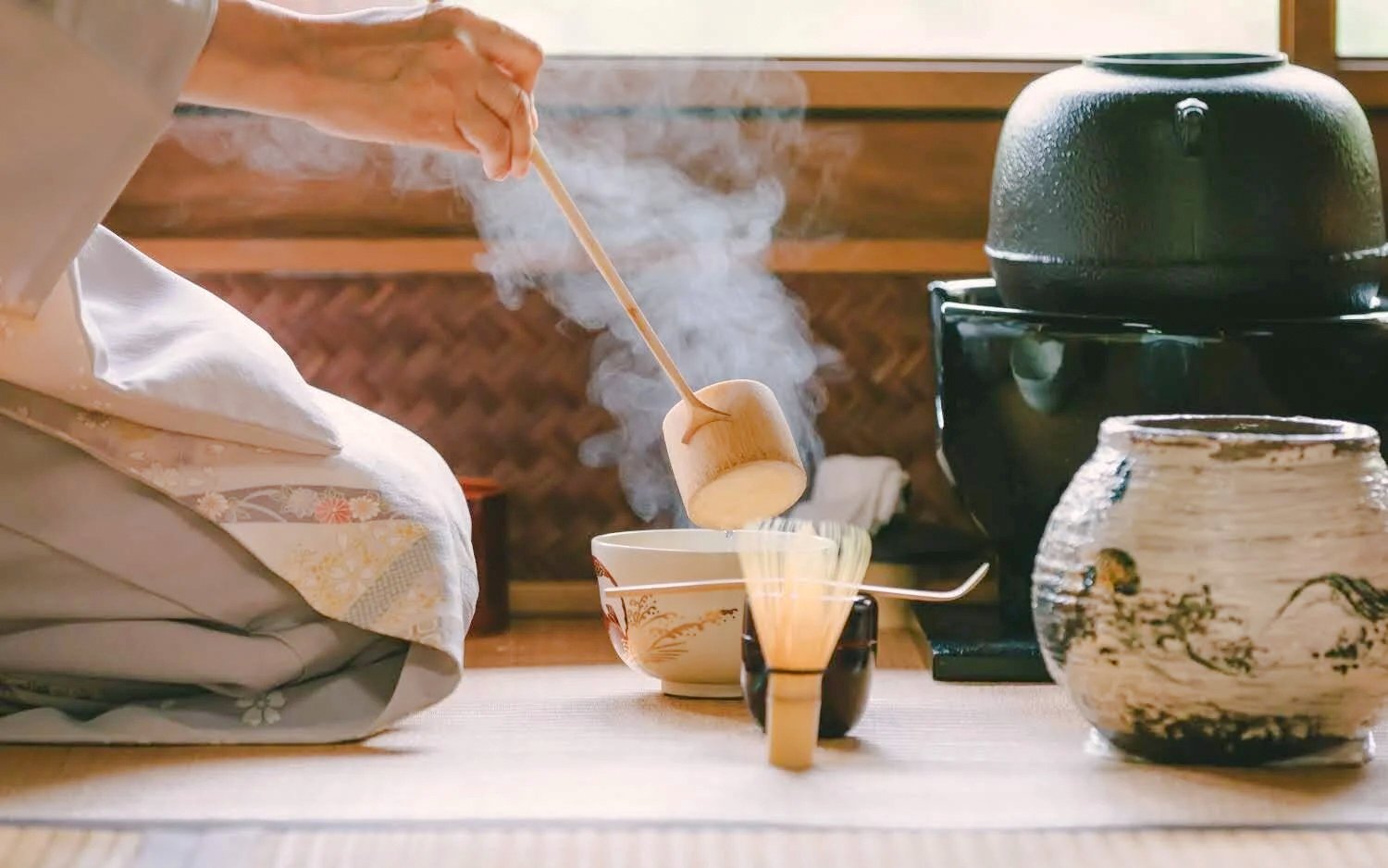 Traditional Japanese tea ceremony with steaming tea bowl and utensils.