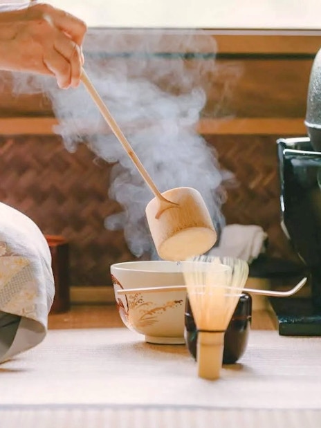 Traditional Japanese tea ceremony with steaming tea bowl and utensils.