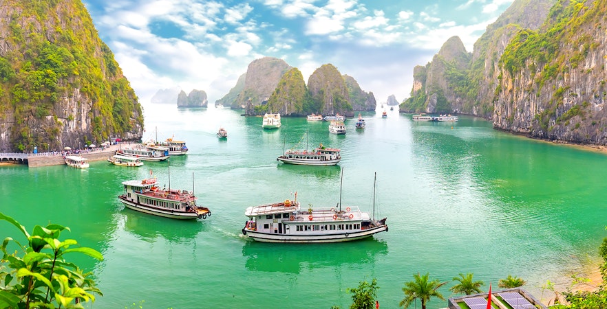 Ha Long Bay limestone karsts and emerald waters with traditional junk boat.