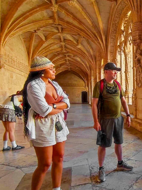 Tourist group with guide inside Jeronimos Monastery, Lisbon, exploring ornate cloisters.