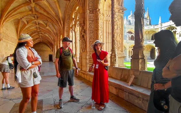 Tourist group with guide inside Jeronimos Monastery, Lisbon, exploring ornate cloisters.