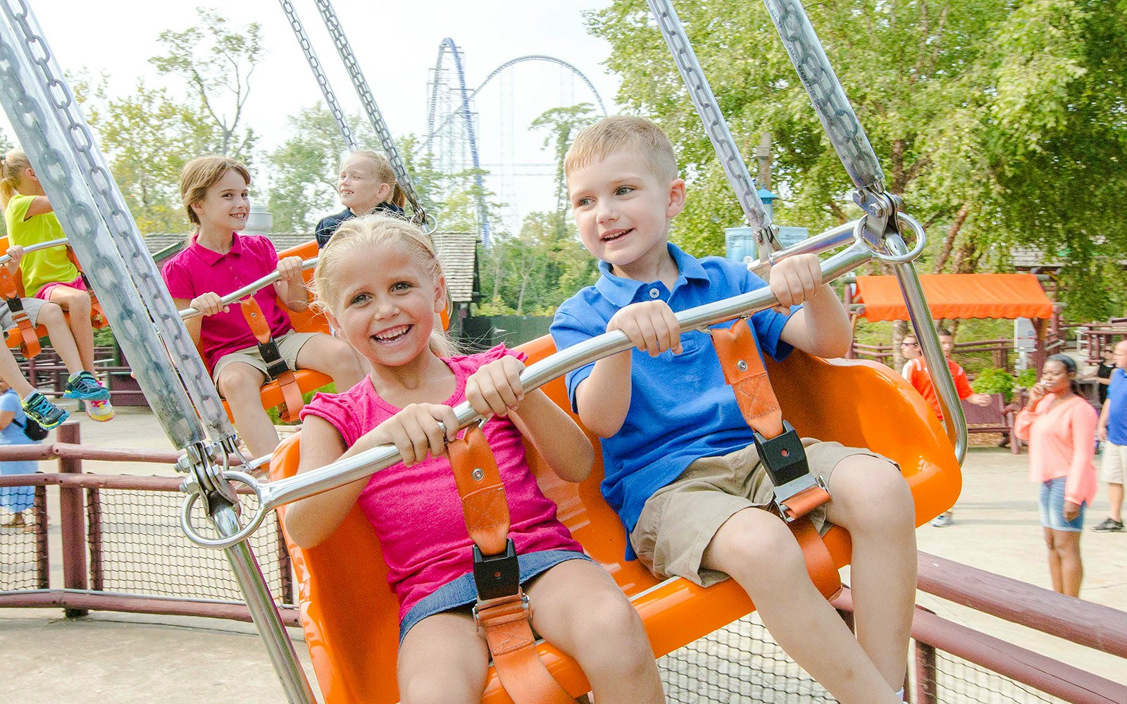 Children enjoying Charlie Brown's™ Wind-Up ride at Cedar Point with roller coaster in background.