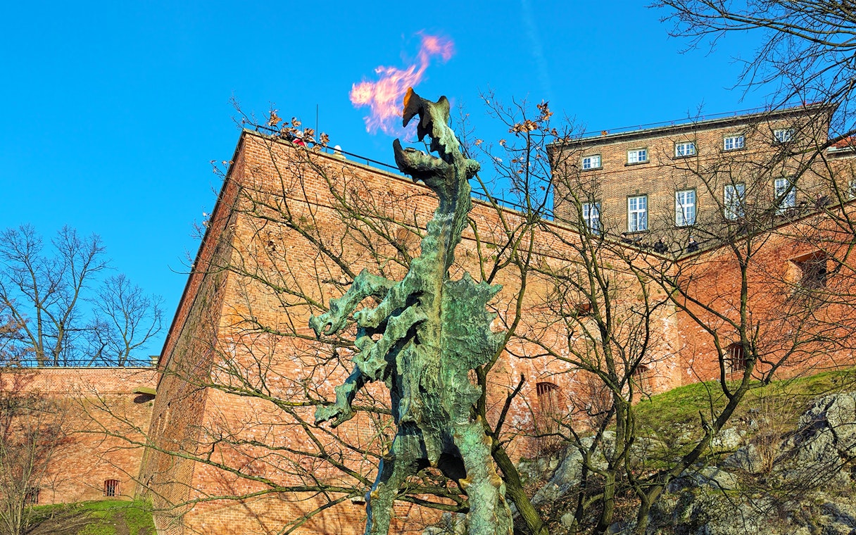 Wawel Dragon statue breathing fire near Wawel Castle walls in Krakow, Poland.