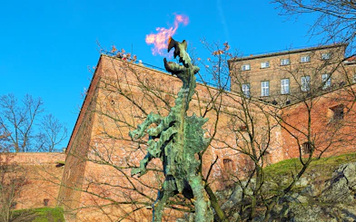 Wawel Dragon statue breathing fire near Wawel Castle walls in Krakow, Poland.