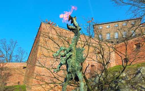 Wawel Dragon statue breathing fire near Wawel Castle walls in Krakow, Poland.