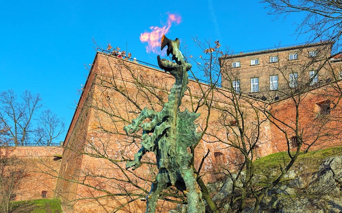 Wawel Dragon statue breathing fire near Wawel Castle walls in Krakow, Poland.
