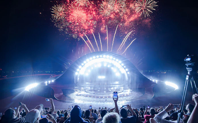 Fireworks display over the Kiss of the Sea Show stage at night.