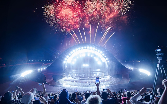 Fireworks display over the Kiss of the Sea Show stage at night.