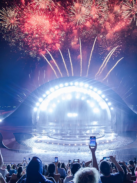Fireworks display over the Kiss of the Sea Show stage at night.