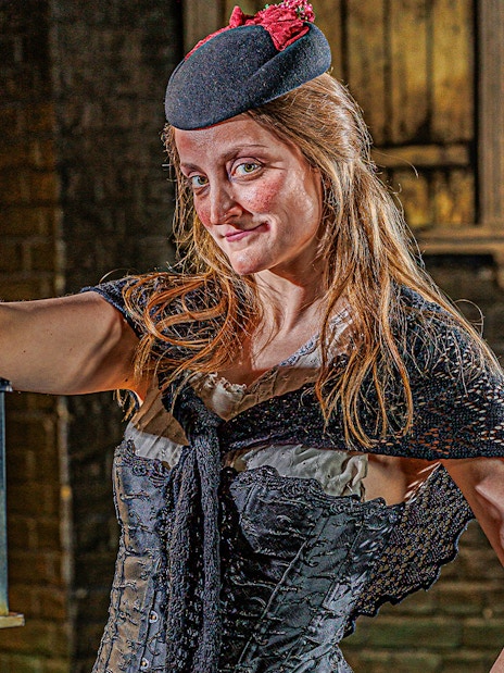 Guide in period costume holding lantern at London Dungeon.