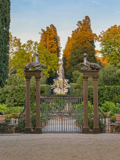 Gate and statues at Boboli Gardens, Florence, with lush greenery and sculptures in the background.