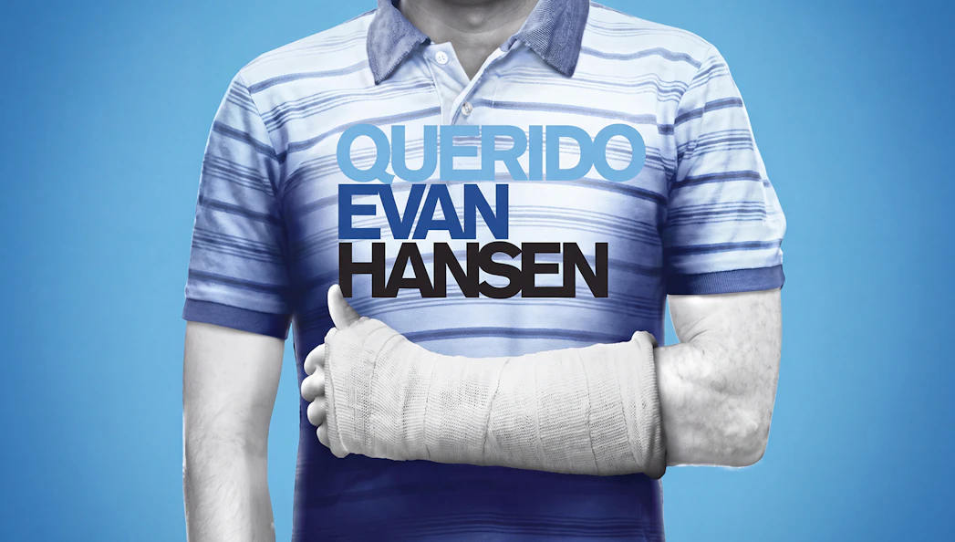 Man in striped shirt with arm cast, text "Querido Evan Hansen" on chest.