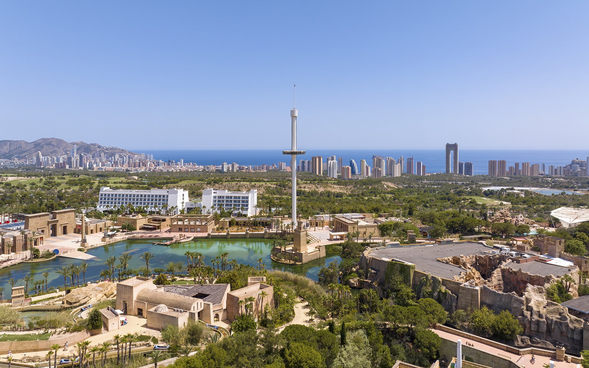 Terra Mitica Benidorm theme park with rides, lagoon, and city skyline in the background.