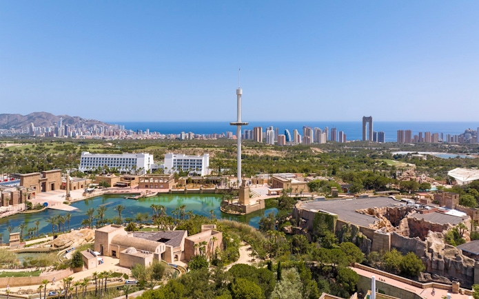 Terra Mitica Benidorm theme park with rides, lagoon, and city skyline in the background.