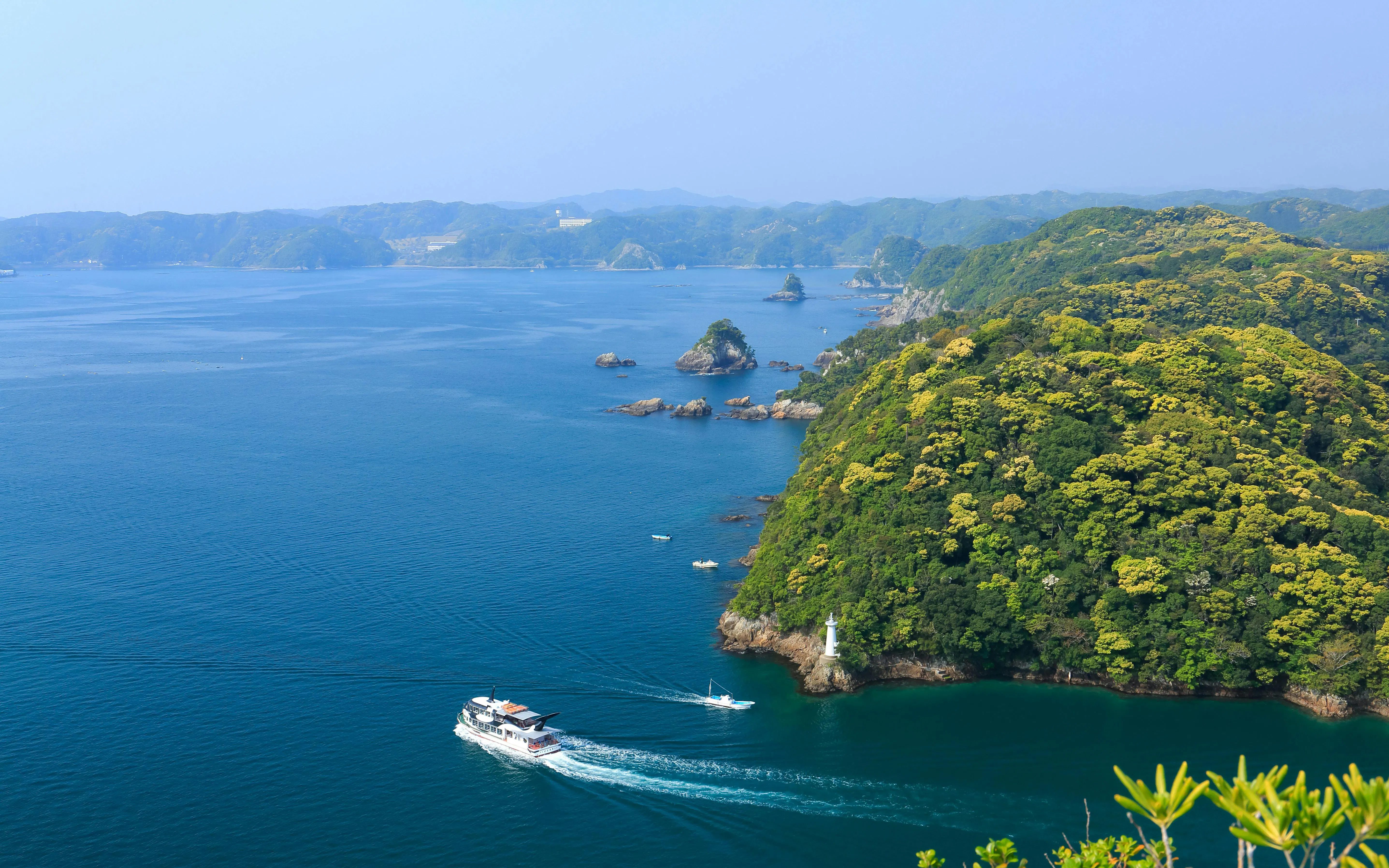 Tour boat navigating around Kinomatsushima's lush green islands and coastal waters.