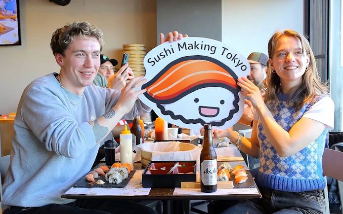 Couple holding sushi sign at Tokyo sushi class in Asakusa.