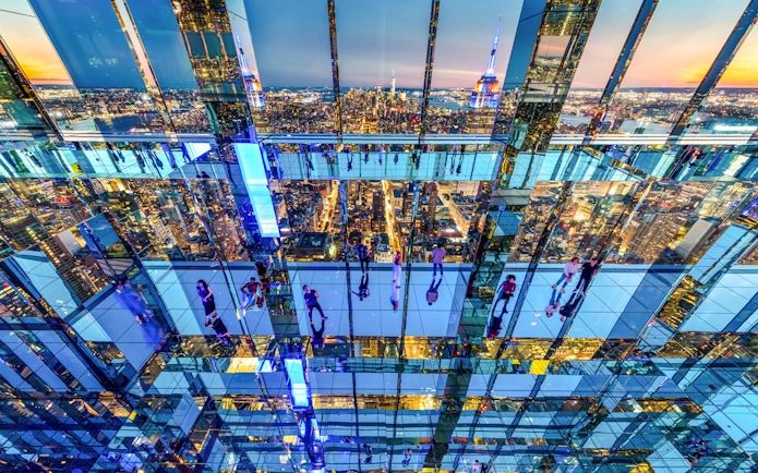 Interior view of SUMMIT One Vanderbilt with mirrored reflections and New York City skyline.