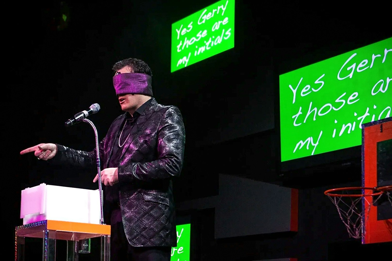 Performer blindfolded on stage during The Mentalist show, pointing at audience.