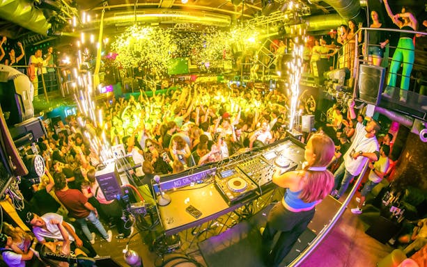 DJ playing at a lively sunset boat party in Prague with a crowd dancing.
