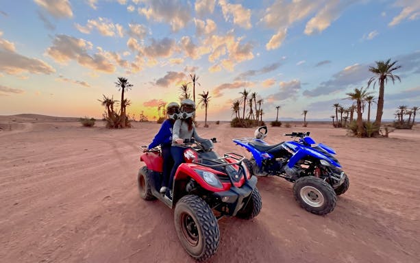 Two people on a quad bike in the palm grove at sunset, Marrakech.