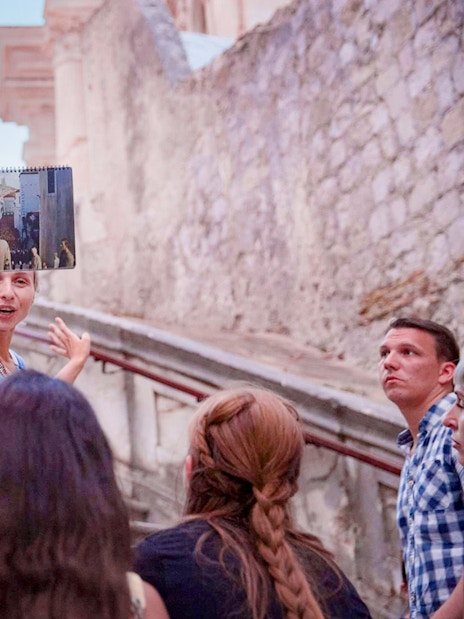 Guide explaining to tourists on Elaphiti Islands tour, holding a photo for reference.