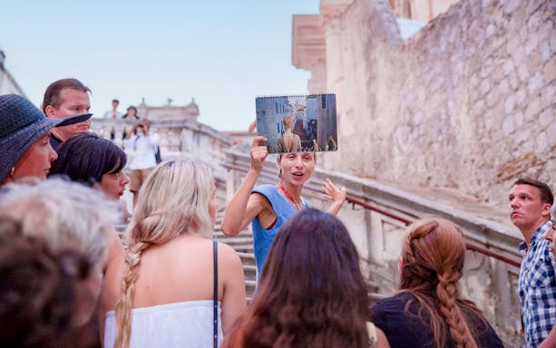 Guide explaining to tourists on Elaphiti Islands tour, holding a photo for reference.