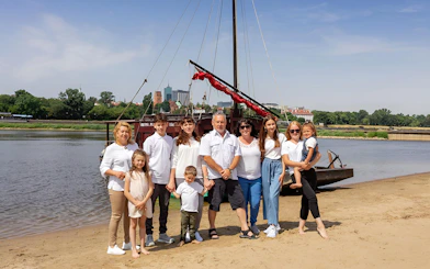 Family posing on the Vistula Riverbank with a traditional Galar boat in the background.