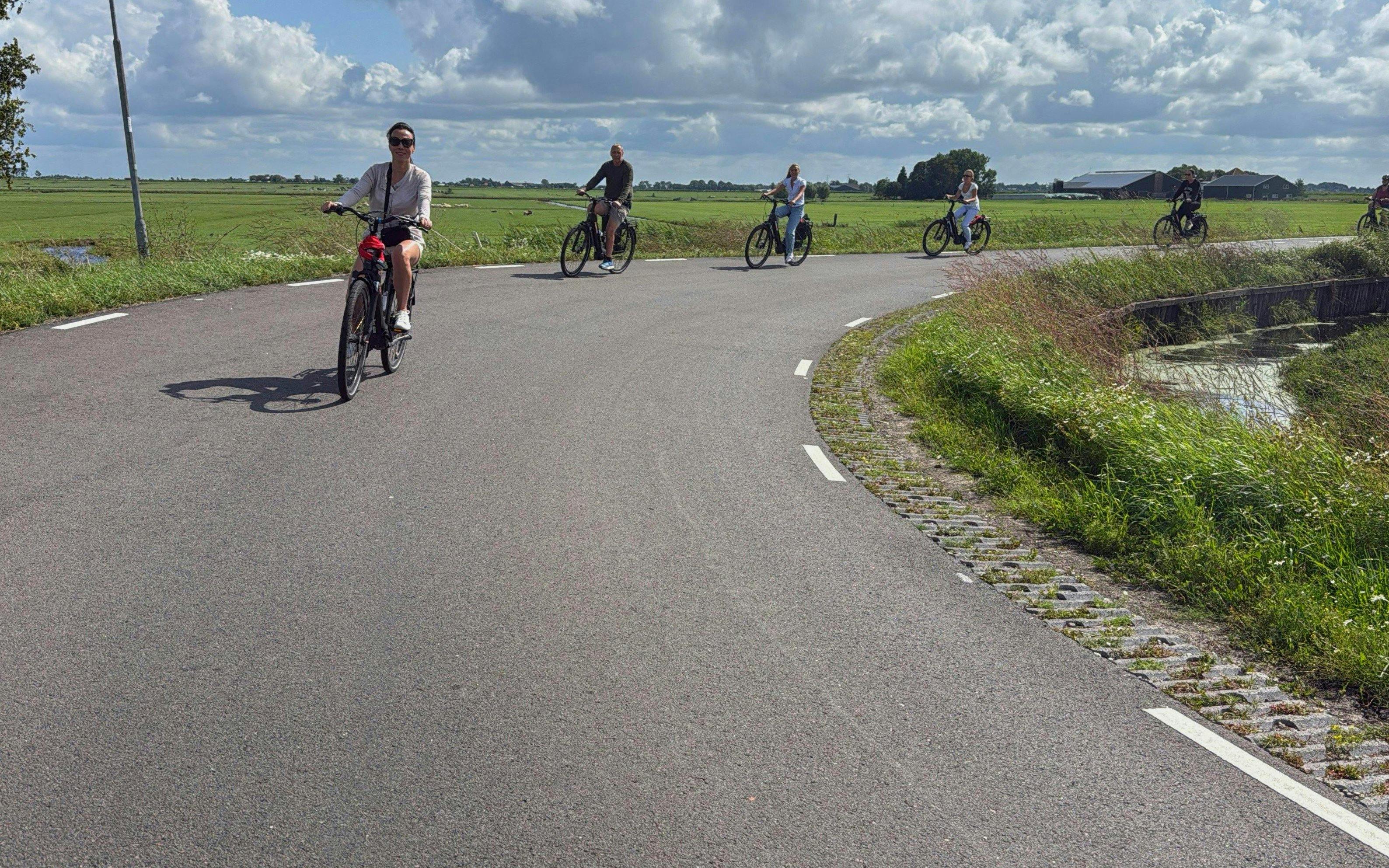Group cycling on e-bikes through scenic countryside road.