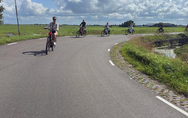 Group cycling on e-bikes through scenic countryside road.