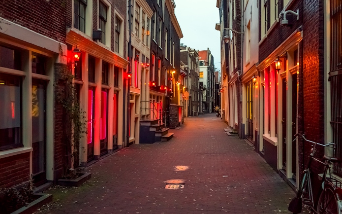 Amsterdam's red light district at night with illuminated windows and narrow street.
