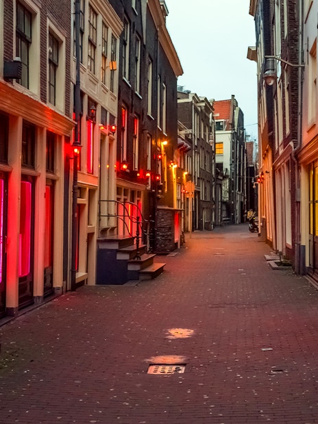 Amsterdam's red light district at night with illuminated windows and narrow street.