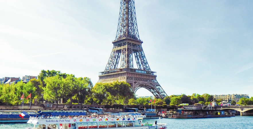 Seine River cruise boat passing by the Eiffel Tower in Paris.