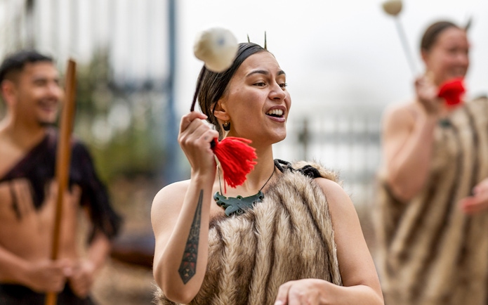 Performer in traditional Māori attire during Te Puia Haka experience, New Zealand.