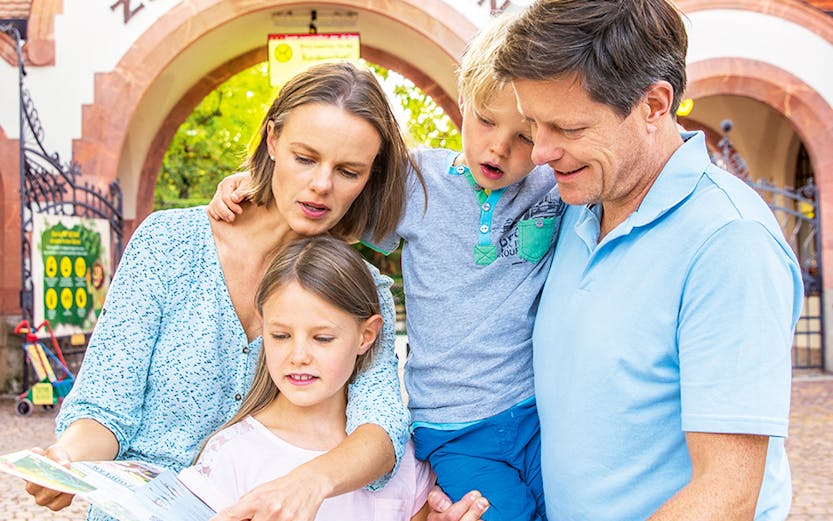Family exploring map at Zoo Leipzig entrance.