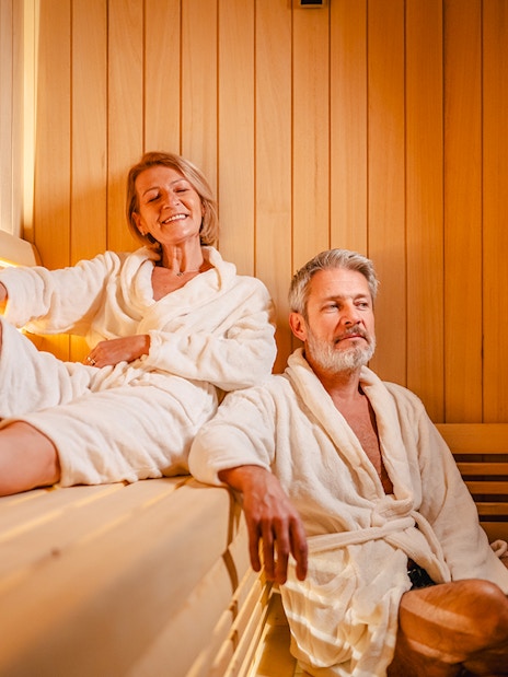 Senior couple relaxing in a wooden sauna.