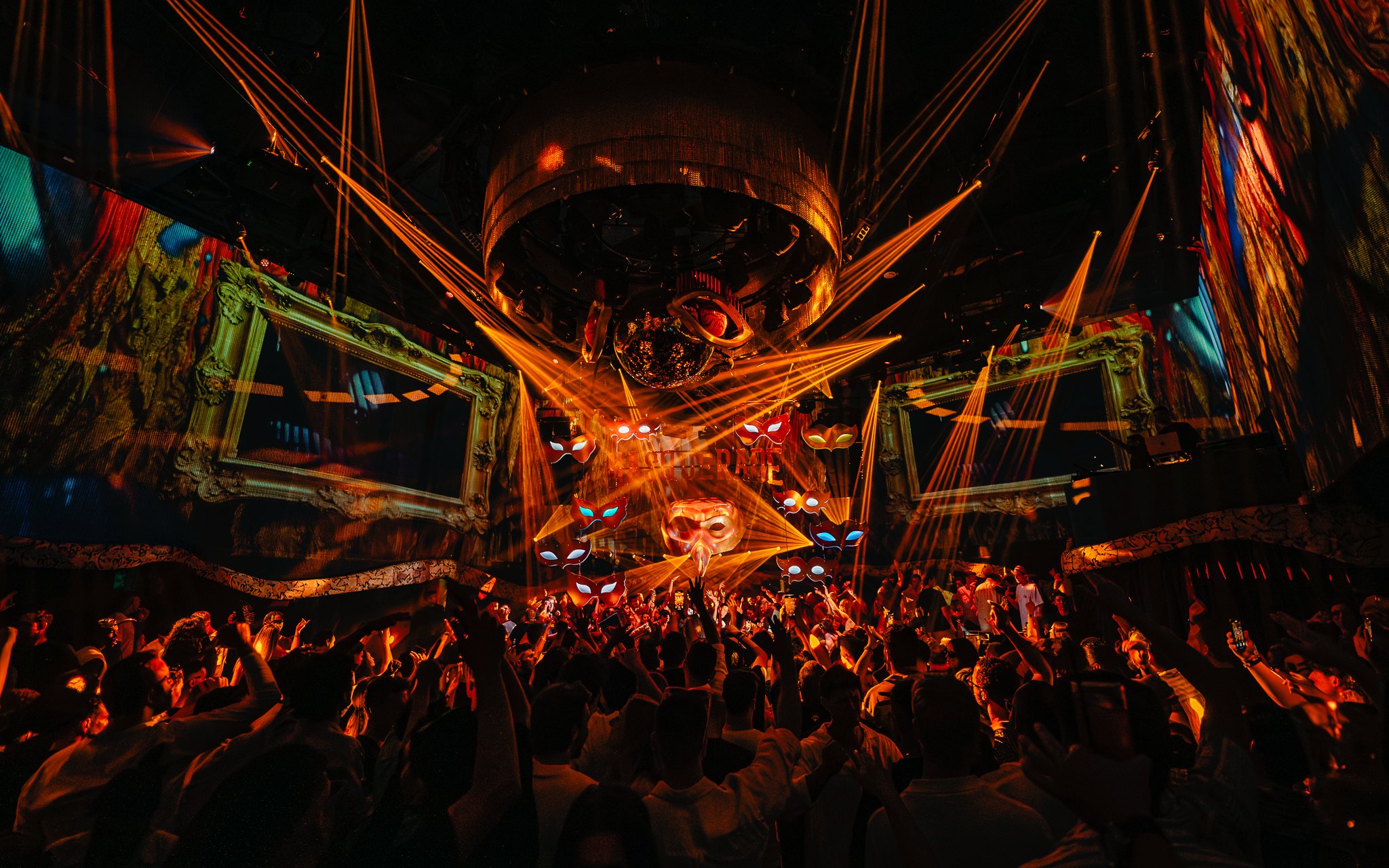 DJ performing at The Masquerade by Claptone, vibrant crowd and lights, Ibiza nightclub.