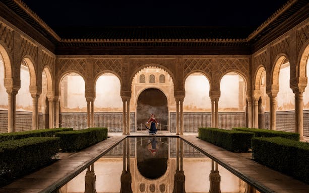 Seville Alcazar courtyard at night with female performer in center.