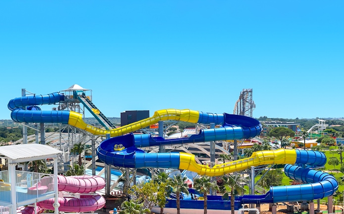 Colorful water slides at Aquashow Water Park, Portugal, with lush greenery in the background.