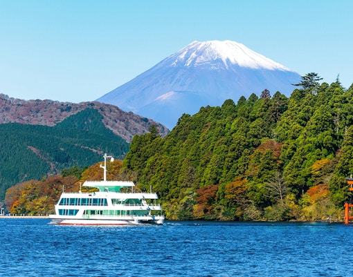 Cruise boat on Lake Ashi with Mt. Fuji and torii gate in the background, Japan.