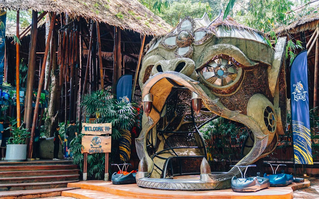 Hanuman World entrance with decorative sculpture and zipline carts in Phuket, Thailand.