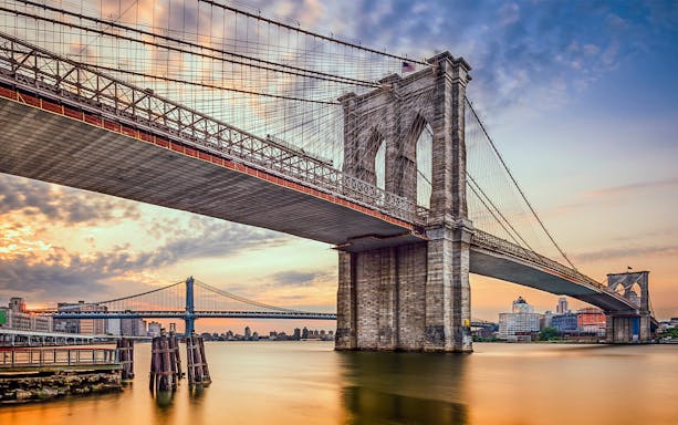 Brooklyn Bridge at sunset, New York City skyline in the background.