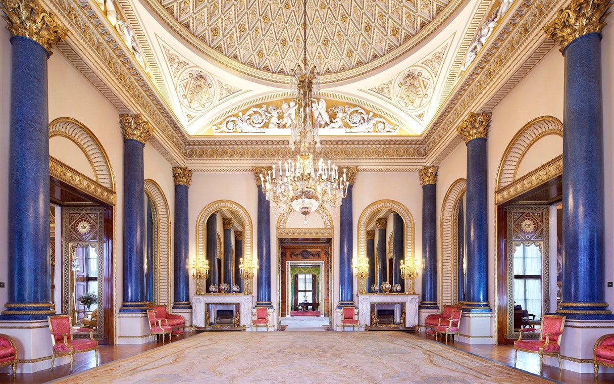 Buckingham Palace State Room with ornate ceiling, chandeliers, and blue columns.
