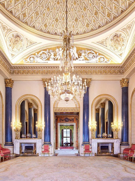Buckingham Palace State Room with ornate ceiling, chandeliers, and blue columns.